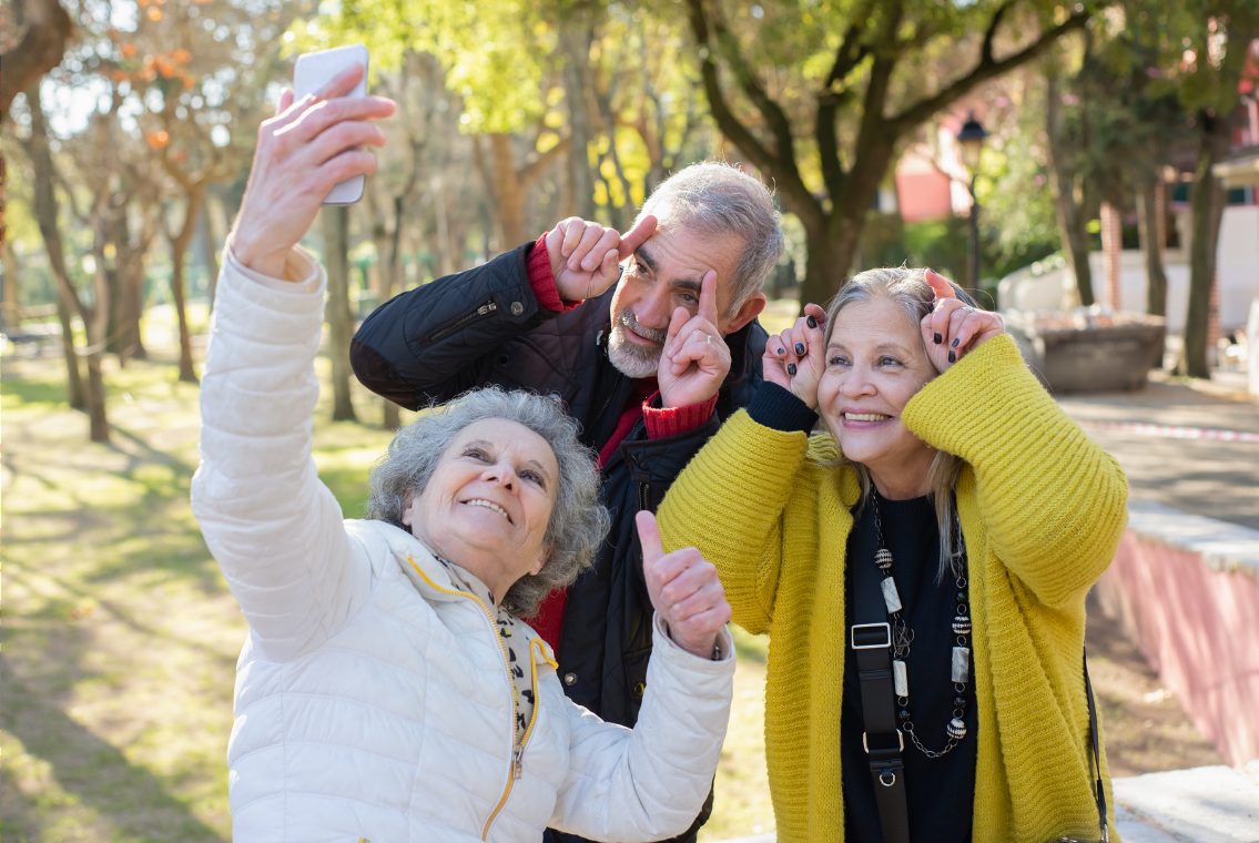 Three friends laughing while taking a selfie outdoors