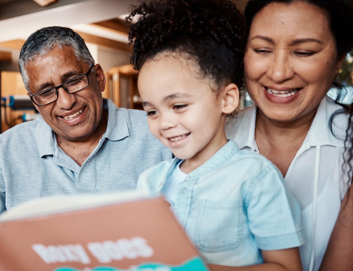 A grandfather, grandmother, and grandchild reading together